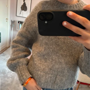 Grå stickad tröja - Säljer en mysig grå stickad tröja med långa ärmar. Perfekt för kyliga dagar och ger en avslappnad look. Passar bra till jeans eller kjol.