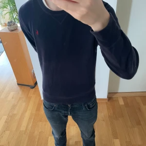 Ralph Lauren finstickad tröja - Säljer en stilren mörkblå finstickad tröja från Polo Ralph Lauren. Tröjan är lite tjockare och passar därför perfekt nu till våren. Den är i storlek 18-20 år fast sitter i storlek S. Tröjan är även väl omhändertagen och därav i bra skick. Hör gärna av er vid frågor eller funderingar!!