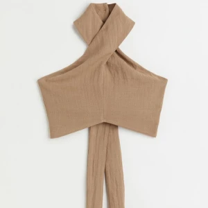 Halterneck topp med öppen rygg  - Brun halterneck topp med knytning i ryggen. Från H&M i Storlek S. Använd 1 gång och inget att anmärka på. Svårt att ta en rättvis egen bild på denna. 75% viskos/25% polyamid