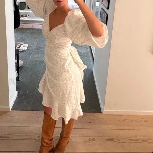 Vacker Adoore vit omlottklänning  - Säljer min superfina vit omlottklänning med puffiga trekvartsärmar och volangdetaljer.💫Man knyter i midjan så man får väldigt fin figur! Använt endast en gång 
