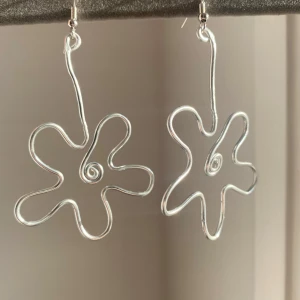Silvriga örhängen i abstrakt form - Unika silvriga örhängen med en abstrakt, virvlande design. De har en kreativ och konstnärlig form som liknar en blomma eller stjärna, perfekt för att ge en stilfull touch till din outfit. - aluminium- kontakta för mer info💕