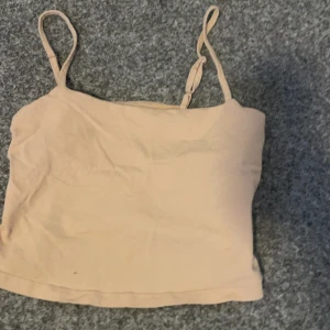 Beige linnetopp från 157 - Säljer en beige linnetopp från 157 i storlek S. Toppen är tillverkad av 95% bomull och 5% elastan, vilket gör den mjuk och stretchig. Perfekt för varma dagar med sina smala axelband.