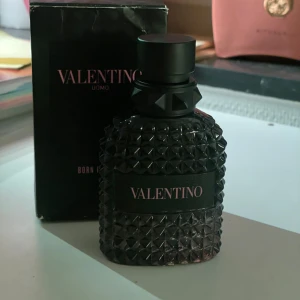 Valentino Uomo Born In Roma EdT - Säljer en elegant parfymflaska från Valentino, Uomo Born In Roma EdT. Flaskan har en lyxig design med ett mönster av små pyramidformade nitar och en svart etikett. Perfekt för den som vill ha en sofistikerad doftupplevelse. 49 ml kvar