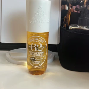 Sol de Janeiro Brazilian Crush Cheirosa 62 - Säljer en Sol de Janeiro Brazilian Crush Cheirosa 62 kroppsmist med doft av pistage och salt karamell. Flaskan är genomskinlig med en vit kork och rymmer 240 ml. Perfekt för att fräscha upp både kropp och hår med en exotisk doft.