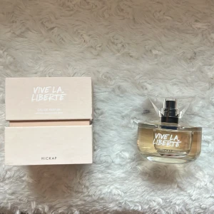 Vive La Liberté Eau de Parfum från Hickap - Upptäck Vive La Liberté Eau de Parfum från Hickap. Denna parfym kommer i en elegant glasflaska med en transparent, geometrisk kork. Förpackningen är stilren och ljus med modern typografi. Perfekt för den som vill känna sig fri och självsäker. Endast testad, den är förvarad i skugga och är som ny! Nypris 499