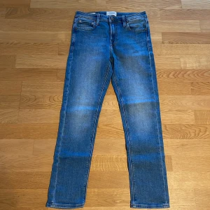 Blå jeans från Jack & Jones - Snygga blå jeans från Jack & Jones, modell Slim Glenn. De har en slim passform och klassisk femficksdesign med dragkedja och knapp. Perfekta för en stilren look.