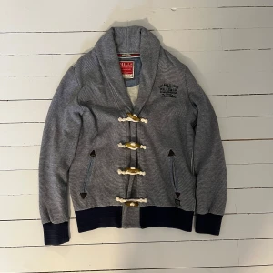 Unik grå cardigan - En snygg unik kofta med feta trä spännen, original storlek medium men sitter som small. Asbra skick och det är bara att höra av sig vid frågor
