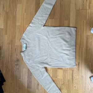 Beige tröja från A Day's March - Säljer en stilren beige tröja från A Day's March. Tröjan har en klassisk design med rund hals och långa ärmar. Perfekt för en avslappnad och snygg look.