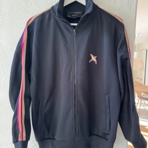Svart track jacket med ränder - Snygg svart track jacket med dragkedja från Axel Arigato. Storlek S  kan gå ner lite vid snabb affär!