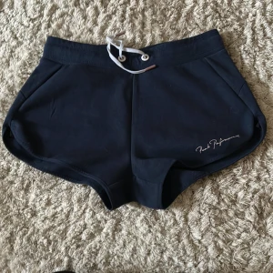 Marinblåa  shorts från Peak Performance - Snygga marinblåa shorts från Peak Performance med snörning i midjan. Perfekta för en aktiv livsstil eller en avslappnad dag. Stilren design med diskret logga på sidan.