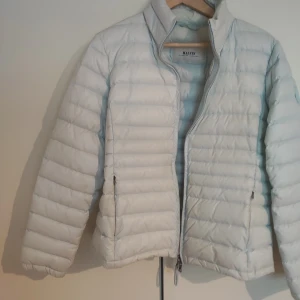 Ljusblå dunjacka från Malvin - Säljer en ljusblå dunjacka från Malvin. Jackan har en quiltad design med dragkedja framtill och långa ärmar. Perfekt för kyligare dagar med sin lätta och naturliga isolering.