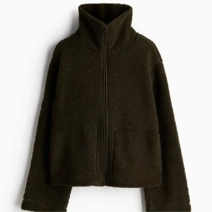 Mörkgrön teddyjacka - Mysig mörkgrön teddyjacka med dragkedja framtill. Perfekt för kyliga höst- och vinterdagar. Jackan har en hög krage och långa ärmar för extra värme. Den är i mycket bra skick och passar perfekt för en avslappnad stil.