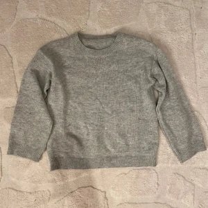 Grå stickad tröja - Säljer en mysig grå stickad tröja i bra skick. Perfekt för höst och vinter med sin varma och bekväma design. Tröjan har långa ärmar och en klassisk rund halsringning. Passar perfekt till jeans för en avslappnad look.