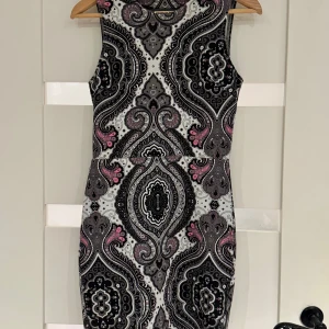Mönstrad ärmlös klänning - Säljer en superfin ärmlös klänning med ett unikt mönster i svart, grått och rosa. Klänningen har en v-ringad rygg och är perfekt för både fest och sommar. Materialet känns mjukt och bekvämt, och den har en tight passform som framhäver figuren. Perfekt för dig som vill sticka ut!