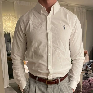 Polo Ralph Lauren skjorta  - En vit skjorta från Polo Ralph Lauren är ett tidlöst plagg i mjukt bomullstyg med perfekt passform. Med klassisk button-down-krage och broderad logotyp på bröstet passar den lika bra till formella tillfällen som till en avslappnad stil. Kan diskutera pris alltid !