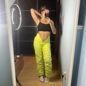 Gröna snygga byxor - Säljer ett par gröna byxor i loose fit. De är högmidjade och har en cool, rynkad design som ger en unik look. Perfekta för att sticka ut på festen eller bara liva upp vardagsstilen. Materialet känns lätt och bekvämt. Passar perfekt för vår och sommar! Går även att sy upp V-ringningen om det önskas. Använda 1 gång. 