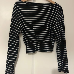 Svart och vit randig tröja från Gina Tricot - Säljer en snygg svart och vit randig tröja från Gina Tricot. Den är croppad och har långa ärmar, perfekt för en casual look. Tröjan är i bra skick och passar perfekt till jeans eller kjol. Perfekt för vår och höst!