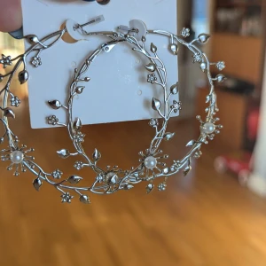 Silvriga örhängen med blommor och pärlor - Superfina stora silvriga örhängen med ett detaljerat blommönster och små pärlor. Perfekta för att ge en elegant touch till din outfit. De är ny.postar inom tre dagar efter köpet 