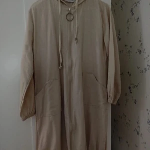 Beige långärmad kofta från Tesettür Dünyası - Säljer en beige långärmad kofta från Tesettür Dünyası i storlek 44. Koftan har en dragkedja framtill och en huva, vilket ger en avslappnad look. Perfekt för höst och vår!