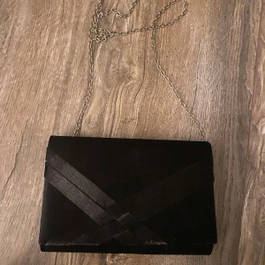 Svart väska med kedja - Säljer en gullig liten axelsrems ”kuvertväska” med kedja. Vet inte varumärket på väskanntyvärr. Pris kan diskuteras 🥰