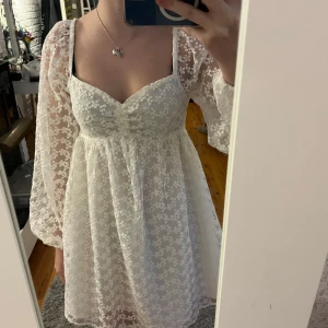 Vit spetsklänning från NA-KD - Säljer en superfin vit spetsklänning från NA-KD i storlek 36. Klänningen har långa ärmar och ett vackert blommigt mönster. Har klippt ur innertyget så ärmarna är endast i spets🫶🏼☺️