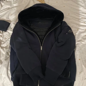 Moose knuckles classic bunny. M - Äkta mörkblå moose knuckles classic bunny med avtagbar svart päls på insidan i storlek M, väldigt fint skick och köpt på NK. Kvitto medföljer med köp. Perfekt för svensk höst, vinter och vår!