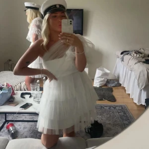 By malina klänning vit - Säljer en superfin vit oneshoulder klänning med volanger. Från by malina som är använd en gång! Perfekt för studenten eller sommarens fester! Den har en luftig och elegant design med flera lager av tyll som ger en romantisk känsla. Klänningen är i mycket bra skick och passar perfekt för en festlig look. 
