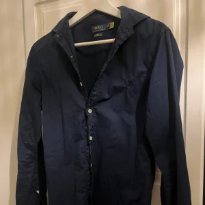 Mörkblå skjorta från Polo Ralph Lauren - Säljer en snygg mörkblå skjorta från Polo Ralph Lauren i storlek S/XS. Skjortan är i slim fit och tillverkad i ett lätt twillmaterial. Perfekt för både vardag och fest! Den har långa ärmar och knappar framtill. 