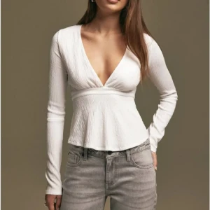 Vit ribbad topp med knyt - Säljer en superfin vit ribbad topp med v-ringning och långa ärmar. Toppen har en snygg knytning i ryggen som ger en extra detalj. Perfekt för både vardag och fest! Hör av er innan ni köper!!❤️Använd 1 gång