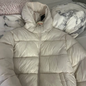 Vit pufferjacka från lager157 - Säljer en superfin vit pufferjacka från lager157 i storlek XS. Jackan är perfekt för kalla dagar med sin fluffiga och varma design. Den har en dragkedja framtill och en hög krage för extra skydd mot kylan. Perfekt för vintern! ❄️