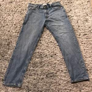 Säljer ett par klassiska blå jeans från Jack & Jones. De har en straight passform och är i bra skick. Perfekta för vardagsbruk och kan matchas med det mesta. Midjan är midwaist och de har en traditionell femficksdesign.