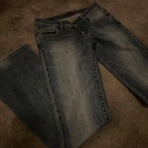 Blåa lågmidjade jeans från Big Star - Säljer ett par klassiska blå jeans från Big Star. De har en snygg färg och en broderad detalj på bakfickan. Säljer vidare pga för små. De är lågmidjade och i strl 27/32z. 