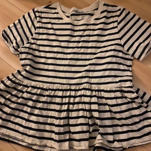 Randig topp från Zara - Säljer en superfin randig topp från Zara i svart och vit. Den har korta ärmar och en söt volangdetalj i nederkanten som ger en extra touch. Skicka för mer info eller bilder🥰