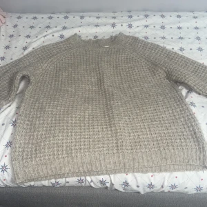 Beige stickad tröja - Mysig beige stickad tröja i bra skick. Perfekt för kyliga höst- och vinterdagar. Tröjan har en normal passform med långa ärmar och ribbade kanter. Den är både stilren och bekväm, vilket gör den till ett måste i garderoben!