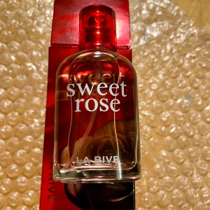 *NY*Sweet Rose parfym från La Rive 30 ml  - Säljer en elegant och romantisk parfym, Sweet Rose från La Rive. Flaskan är stilren och röd, perfekt för att ge en touch av lyx. Doften är blommig och söt, idealisk för både vardag och speciella tillfällen. Förpackningen är också röd med en vacker rosdetalj. Utgångsdatum är 11/2027.