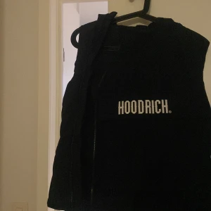 Svart väst från Hoodrich - Säljer en svart väst från Hoodrich i bra skick. Västen har en dragkedja framtill och är perfekt för höst och vår. Den är stilren och passar till många olika outfits.