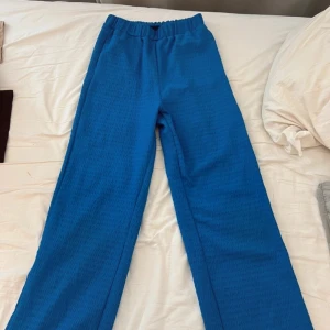 Blå byxor med resårmidja - Säljer ett par snygga blå byxor med resårmidja. De har en loose passform och är perfekta för en avslappnad stil. Passar bra till både vardag och chill. Perfekta för höst och vår!