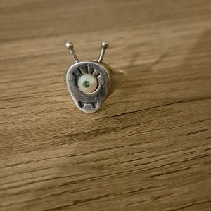 Unik silverring med ögonmotiv - Säljer en supercool ring i silver med ett unikt ögonmotiv. Ringen har en rund form med ett öga i mitten och två små antenner som sticker upp. Perfekt för dig som vill ha något annorlunda och iögonfallande! 🛸