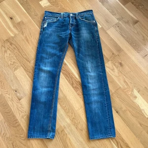 Blå jeans från Dondup - Säljer ett par snygga jeans från Dondup. De är i en härlig blå färg med lite slitningar för en fräsch look. De är i väldigt bra skick och är använda sparsamt. Perfekta för både vardag och fest!
