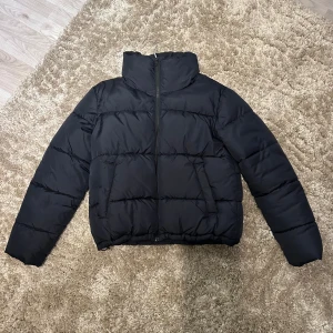 Svart puffer-jacket - Svart puffer-jacket från bikbok som knappt är använd nånting. Inga defekter på jackan. Har en dragsko nertill så man kan välja hur jackan ska vara formad, två fickor som stängs med knappar och har en dragkedja för att stänga jackan💓  Nypris 699kr