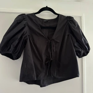 Svart blus med puffärmar - Säljer en svart blus med puffiga kortärmar och knytning framtill. Den populära från Gina tricot! 