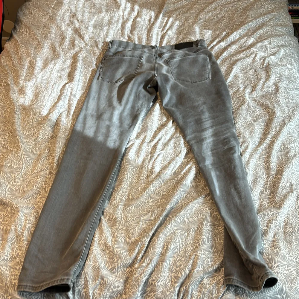 Säljer ett par snygga grå jeans från J.Lindeberg. De har en slim passform och är i storlek 31/32. Perfekta för både vardag och fest! 🖤. Jeans & Byxor.