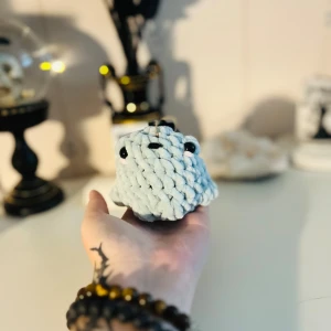 Handgjord stickad figur i ljusblått garn - En supergullig handgjord virkad groda i ljusgrön garn. Den har små svarta ögon och en söt liten mun. Perfekt som dekoration eller som en liten kompis att ha på skrivbordet. Den är mjuk och mysig att hålla i. Perfekt present till någon som älskar djur