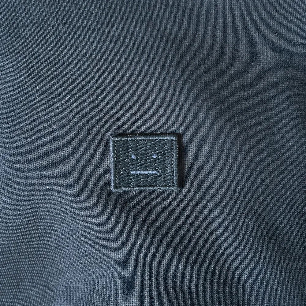 Säljer en stilren svart tröja från Acne Studios. Den har en enkel design med ett diskret broderat ansikte på bröstet. Tröjan är långärmad och perfekt för både vardag och fest. Den är i bra skick och passar till det mesta i garderoben. Nypris≈2800kr💸. Tröjor & Koftor.