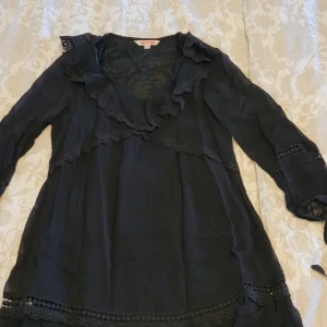 Svart klänning INDISKA - Helt ny, endast testad! Jättefin klänning med söta volangdetaljer och knytband i ärmsluten. Storlek xs