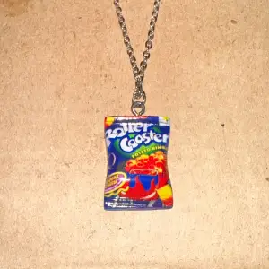 Unikt halsband med ett hänge som ser ut som en Roller Coaster-potatischips-påse. Kedjan är i silverfärg och hänget har en färgglad design med blå, röd och gul färg. Perfekt för den som vill ha något annorlunda och roligt!