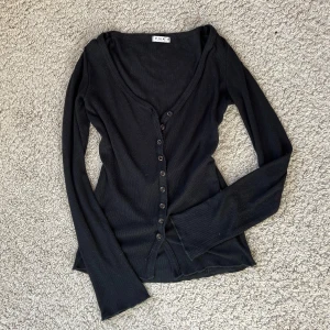 Kofta - Svart kofta från Vila med knappar och fint diskret mönster!