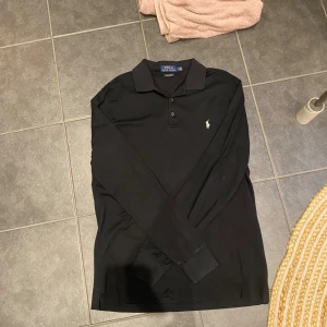 Svart polo piké långärmad - Detta är en svart långärmad piké i märket polo Ralph lauren. Den är storlek medium och är i väldigt bra skick. Vid fler frågor är det bara att skicka