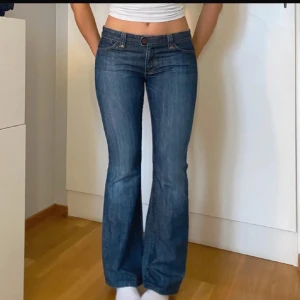 Blå bootcut jeans - Snygga blå bootcut jeans med låg midja och klassisk femficksdesign.. De har en knapp och dragkedja framtill.