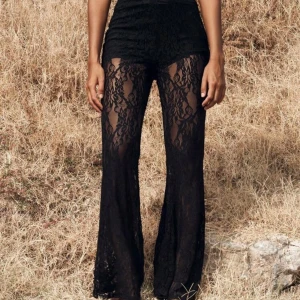 Svarta spetsbyxor - Snygga svarta byxor i spets med hög midja och utsvängda ben. Perfekta för en trendig look med en unik stil. Passar bra till en enkel topp eller blus.